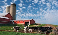 a farm with cows grazing in front of a silo