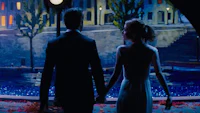 a man and woman holding hands in front of a fountain