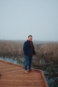 a man standing on a wooden dock in the fog
