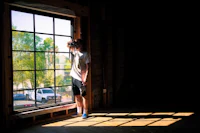 a boy standing in front of a window in an unfinished building