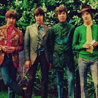 the beatles posing for a photo in front of a garden