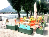 a group of colorful chairs on a sidewalk near a lake