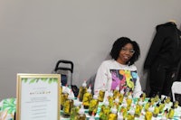 a woman sits at a table with a table full of products