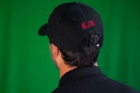 the back of a man wearing a black hat with red lettering