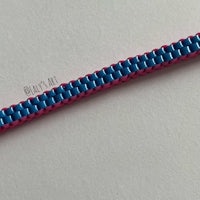 a blue and pink braided bracelet on a white surface