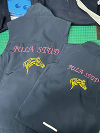 a group of school uniforms with embroidered logos on them