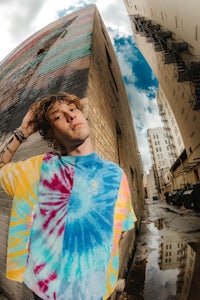 a man wearing a tie dye t - shirt in front of a building