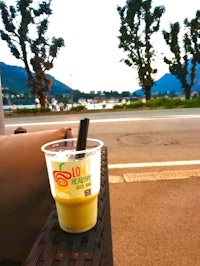 a cup of juice sitting on a table in front of a lake