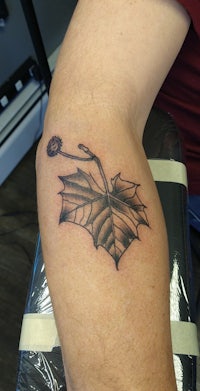 a tattoo of a leaf on a man's arm