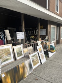 a display of framed pictures on a sidewalk in front of a building