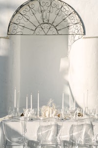 a white table setting with clear glass chairs and candles