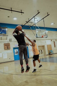two men playing basketball in a gym
