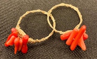 a pair of red coral hoop earrings on a black surface