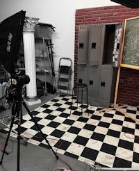 a black and white checkered room with a camera and a tripod