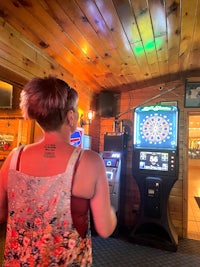 a woman playing a game of darts in a bar