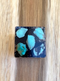 a black and turquoise stone ring on top of a wooden table