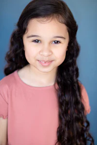 a young girl with long curly hair posing for a photo