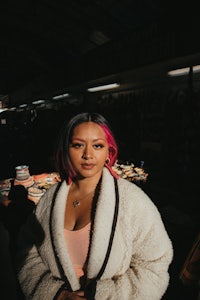 a woman with pink hair standing in a market