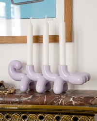a purple candle holder sits on top of a mantel