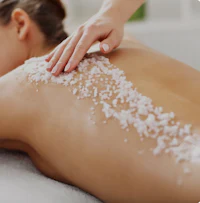 a woman getting a back massage with sea salt