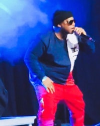 a man in a red jacket and red pants is singing into a microphone