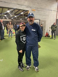 a man and a girl standing next to each other in a baseball field