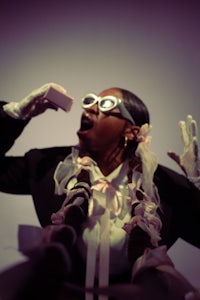 a woman in a suit and glasses is holding a cell phone