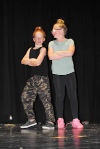 two girls standing on a stage with their arms crossed