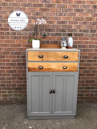 a grey and wood sideboard in front of a brick wall