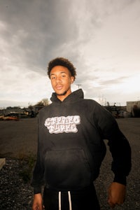 a young man in a black hoodie standing in a parking lot