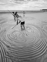a group of people are making sand art on the beach