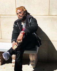a man with dreadlocks sitting on a bench