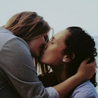 two women kissing each other on the beach