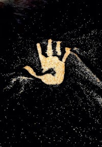 a hand is drawn in the sand on a black background