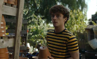 a young man in a striped shirt standing next to pots