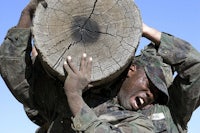 a soldier is carrying a large piece of wood