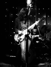 a black and white photo of a man playing a guitar in a dark room