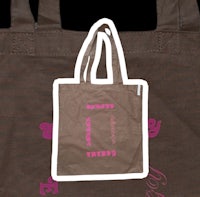 a brown tote bag with pink writing on it