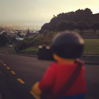 a lego figure on a road with a city in the background