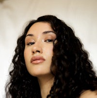 a woman with long curly hair posing for a photo