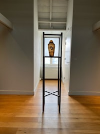 an empty room with a wooden floor and a vase on a stand