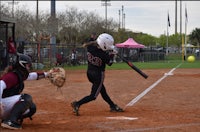 a girl is swinging a bat at a ball