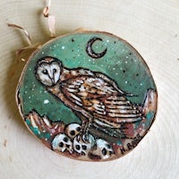 an owl sits on a piece of wood with skulls on it