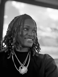 a black and white photo of a woman with dreadlocks sitting on a bus