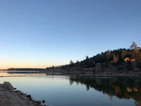 a lake surrounded by rocks and trees at sunset