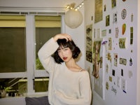 a woman is posing in front of a wall