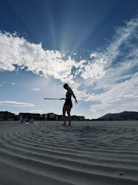 a woman is standing on a beach with a surfboard