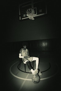 a man sitting on a chair in a basketball court