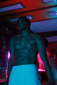 a man with tattoos standing in a room with neon lights