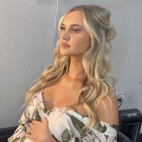 a pregnant woman in a floral dress sitting in a chair